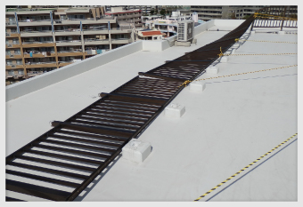 陸屋根に設置されていた長い柵が倒れた状態